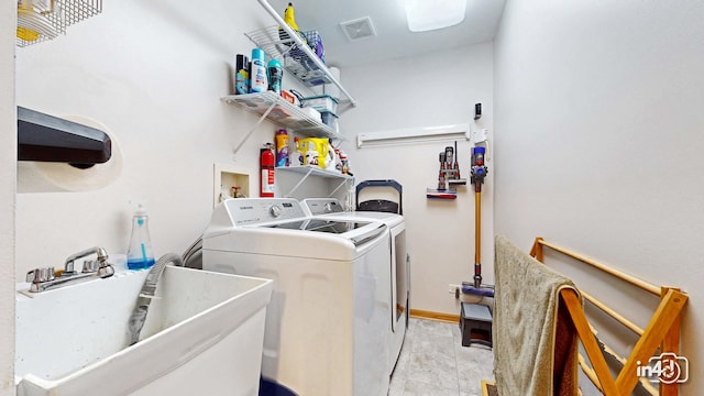 washroom with laundry area, visible vents, a sink, baseboards, and separate washer and dryer