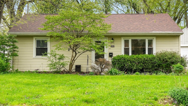 ranch-style home with a shingled roof and a front lawn
