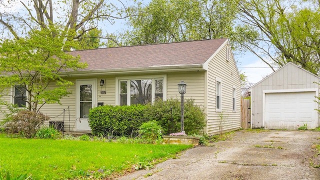view of front facade featuring a shingled roof, an outdoor structure, aphalt driveway, and a detached garage