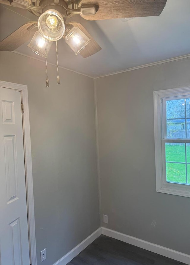 unfurnished room with baseboards, ceiling fan, ornamental molding, and dark wood-style flooring