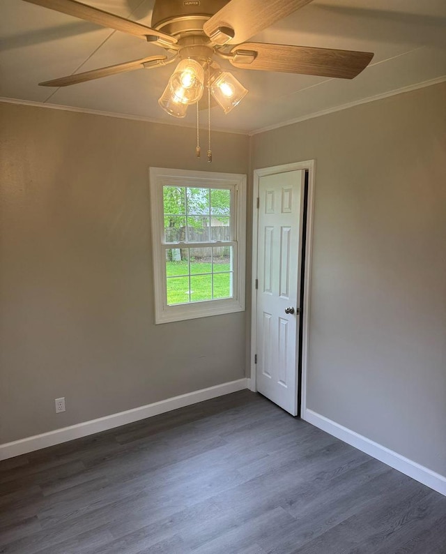spare room with ceiling fan, ornamental molding, baseboards, and dark wood-type flooring