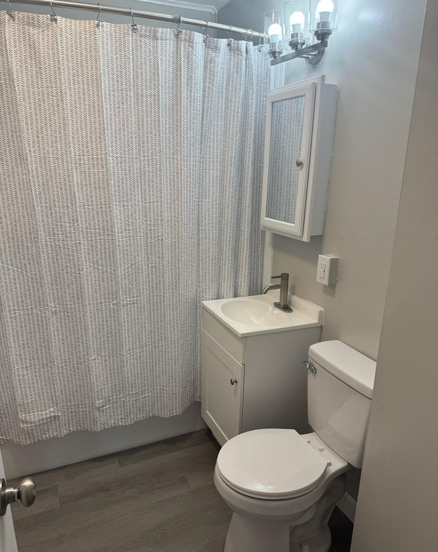 bathroom with an inviting chandelier, vanity, toilet, wood finished floors, and curtained shower
