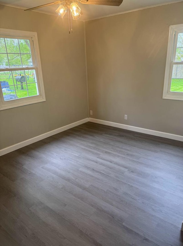 spare room featuring baseboards, ornamental molding, ceiling fan, and dark wood-type flooring