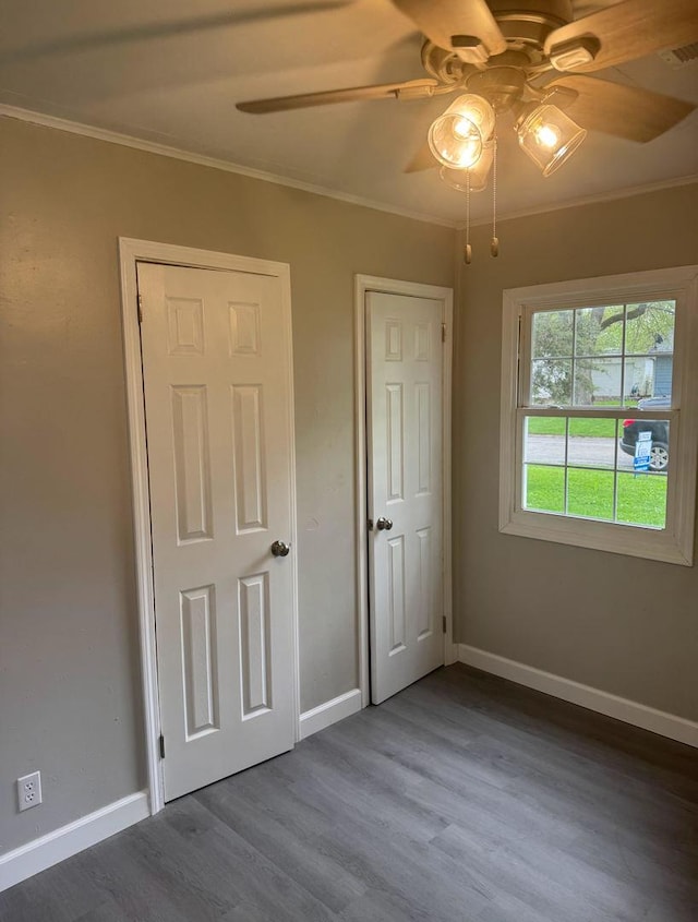 unfurnished bedroom with baseboards, ornamental molding, and wood finished floors