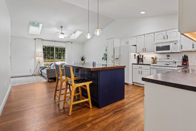 1318 Ridge Pointe Dr, Monticello, IL 61856 - kitchen featuring white cabinets, dark wood-style floors, vaulted ceiling with skylight, white appliances, and a breakfast bar area