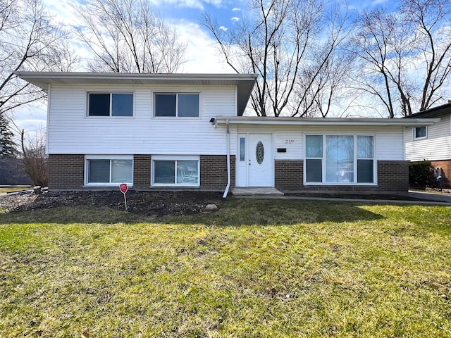 split level home featuring a front yard and brick siding