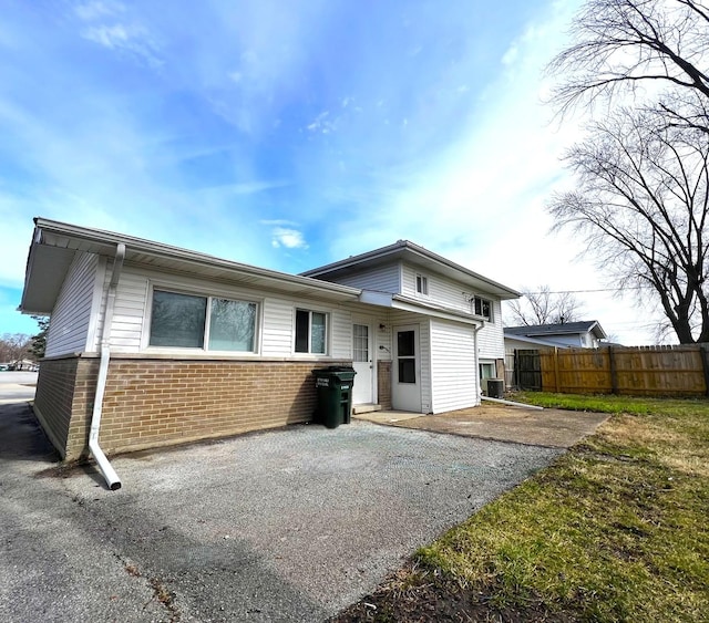 back of property featuring driveway, a patio area, fence, and brick siding