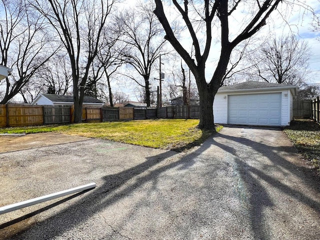 view of yard with a fenced backyard, an outdoor structure, a garage, and driveway