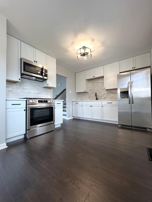 kitchen featuring baseboards, white cabinetry, decorative backsplash, and appliances with stainless steel finishes