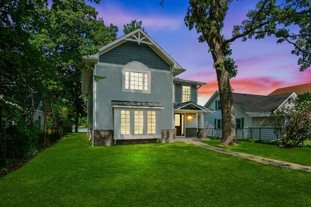 2015 N Woodlawn Park Ave, Mchenry, IL 60051 - back of property featuring stone siding, a standing seam roof, a yard, metal roof, and fence