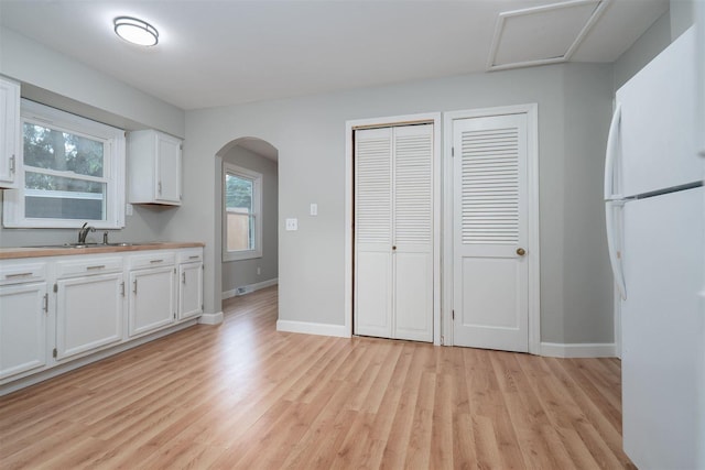 212 Keiser Ave, Normal, IL 61761 - kitchen featuring freestanding refrigerator, light wood-style flooring, arched walkways, and white cabinetry