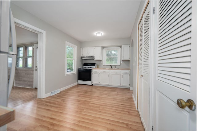 212 Keiser Ave, Normal, IL 61761 - kitchen with white gas stove, white cabinets, light wood finished floors, light countertops, and under cabinet range hood