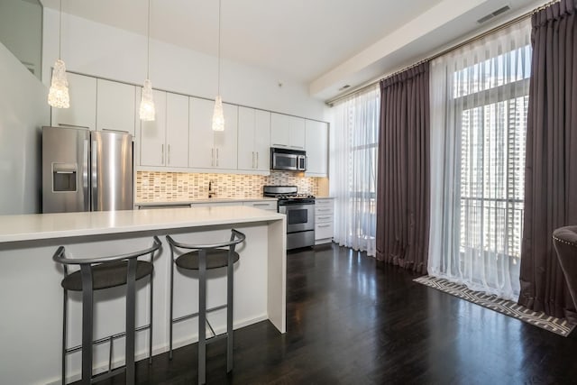 kitchen with stainless steel appliances, a kitchen bar, backsplash, and light countertops