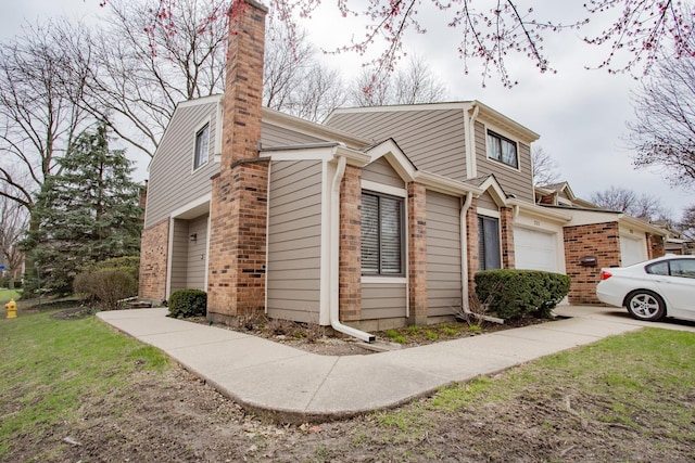 view of property exterior featuring brick siding, an attached garage, a lawn, and a chimney