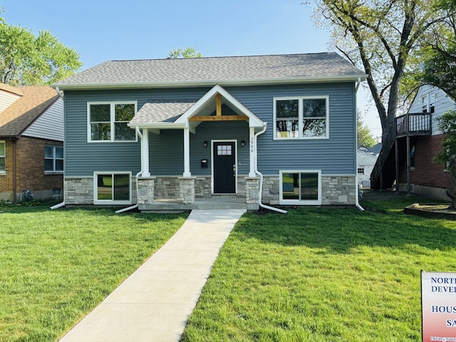 view of front of home featuring a front lawn, a shingled roof, and stone siding