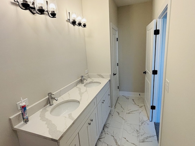 bathroom featuring marble finish flooring, double vanity, a chandelier, and baseboards