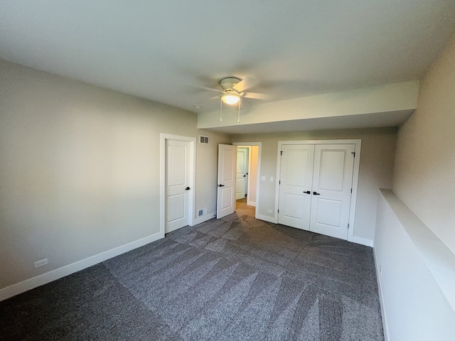 unfurnished bedroom with dark carpet, baseboards, a ceiling fan, and a closet