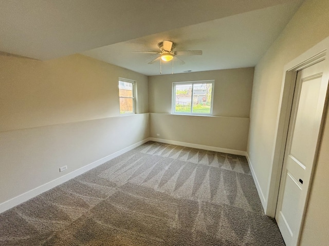 carpeted empty room with a ceiling fan and baseboards
