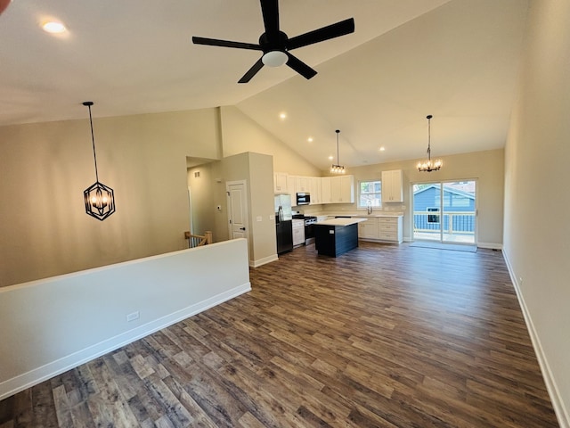 unfurnished living room featuring a chandelier, dark wood-style flooring, high vaulted ceiling, ceiling fan, and baseboards