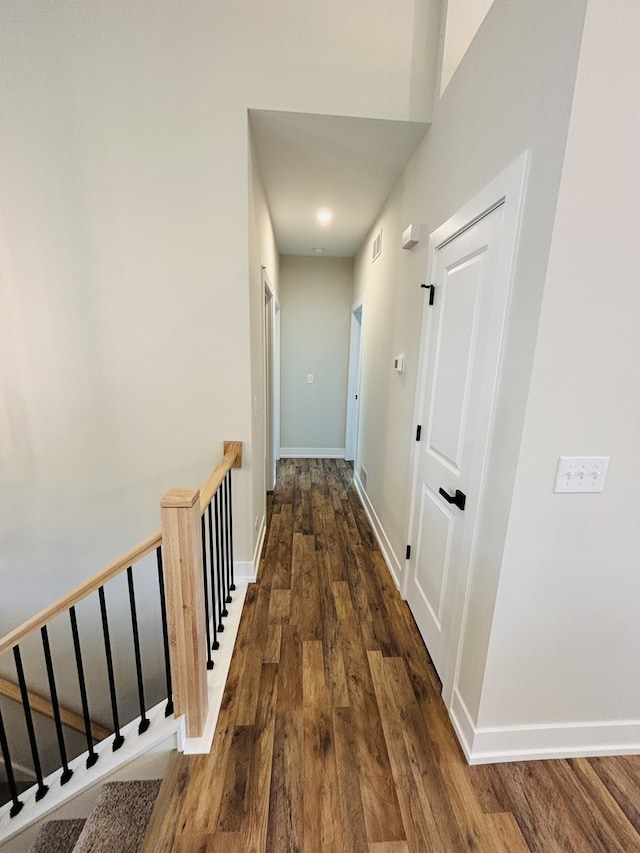 corridor with wood finished floors, baseboards, and an upstairs landing