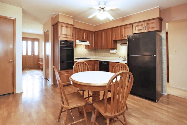 kitchen with a sink, a ceiling fan, under cabinet range hood, a warming drawer, and black appliances