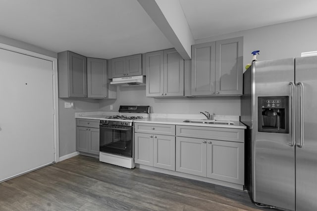 kitchen with stainless steel refrigerator with ice dispenser, gray cabinets, under cabinet range hood, gas stove, and a sink
