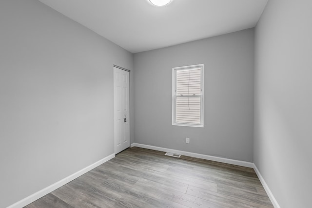 empty room with wood finished floors, baseboards, and visible vents