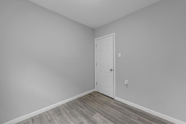 spare room with baseboards and wood finished floors