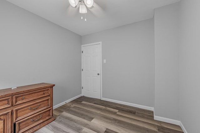 unfurnished room with wood finished floors, baseboards, and a ceiling fan