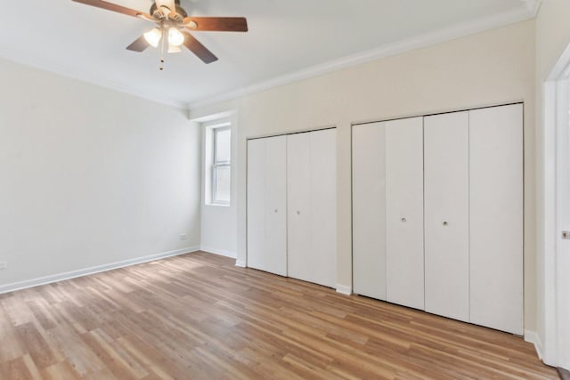 2317 W Wolfram St Unit 211, Chicago, IL 60618 - unfurnished bedroom featuring two closets, crown molding, light wood finished floors, baseboards, and a ceiling fan