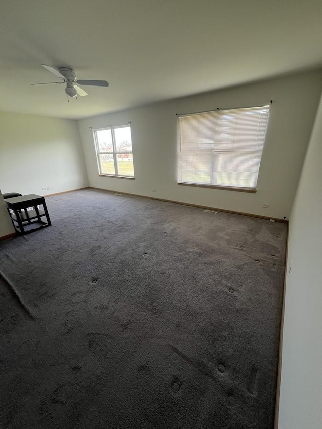 empty room featuring carpet flooring, baseboards, and ceiling fan
