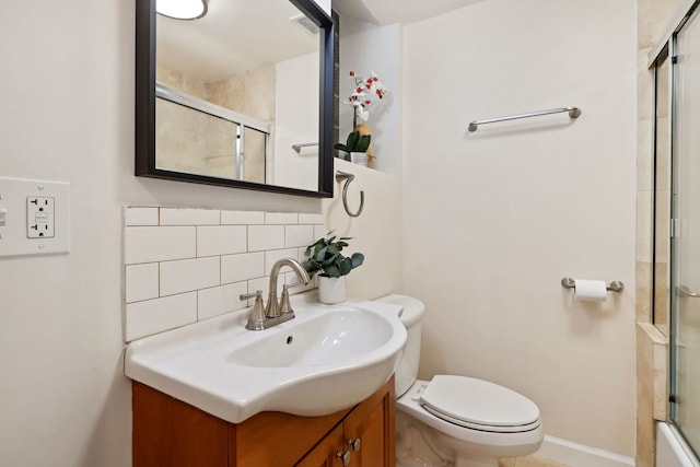 full bath featuring a shower with door, toilet, vanity, baseboards, and decorative backsplash