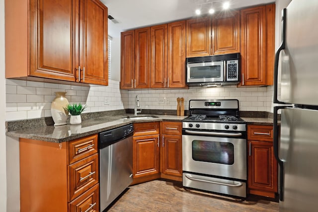 kitchen featuring a sink, brown cabinets, stainless steel appliances, dark wood finished floors, and visible vents