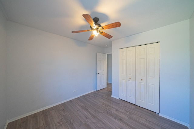 unfurnished bedroom featuring ceiling fan, baseboards, wood finished floors, and a closet