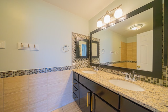 full bath with tile patterned flooring, a sink, double vanity, and tile walls