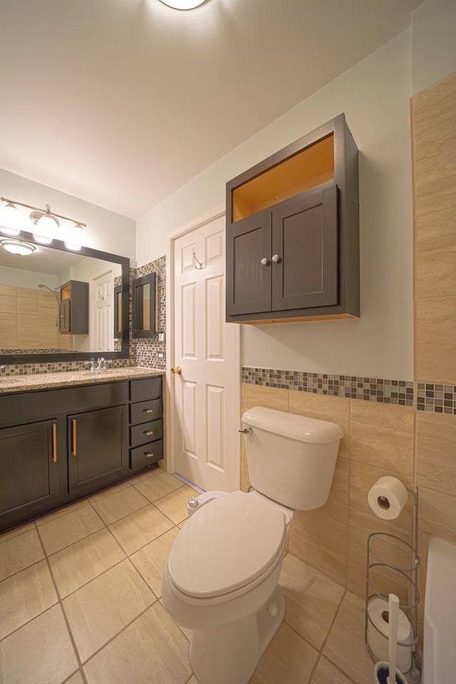 bathroom featuring toilet, vanity, tile patterned floors, and tile walls