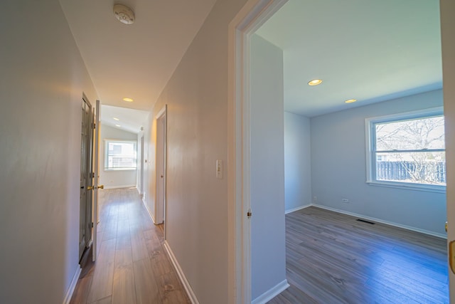 corridor featuring baseboards, wood finished floors, visible vents, and recessed lighting