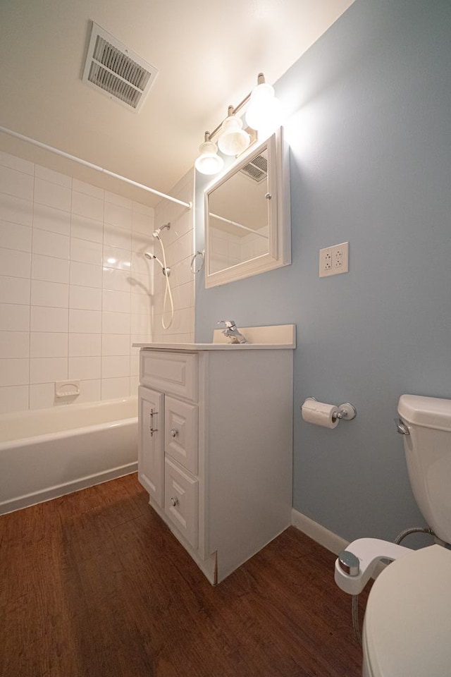 full bath featuring wood finished floors, visible vents, toilet, vanity, and baseboards