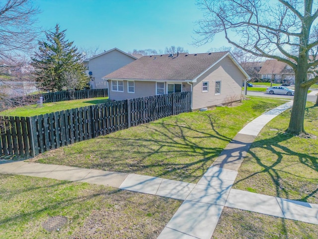 exterior space with fence, a yard, and a shingled roof