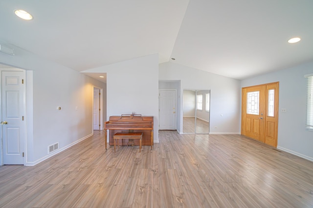 unfurnished living room with vaulted ceiling, light wood-style floors, visible vents, and baseboards