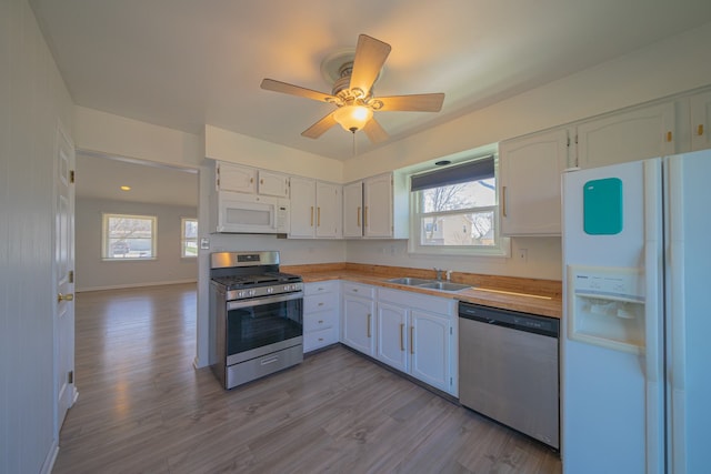 kitchen featuring a sink, white cabinetry, wood finished floors, ceiling fan, and appliances with stainless steel finishes