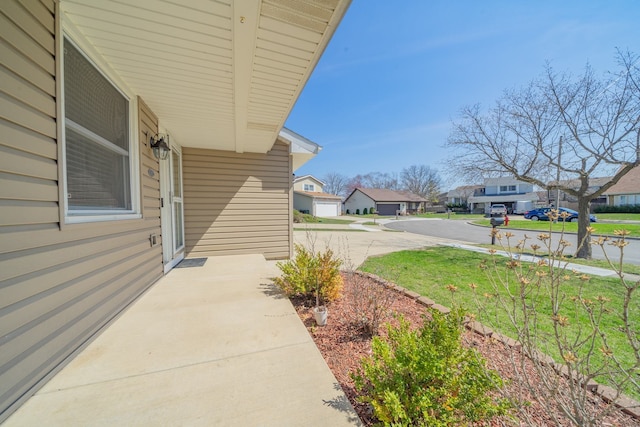 view of yard featuring driveway, a residential view, and covered porch