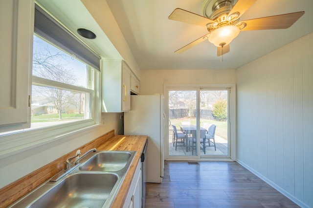 kitchen with white cabinets, wood finished floors, a sink, freestanding refrigerator, and wood counters