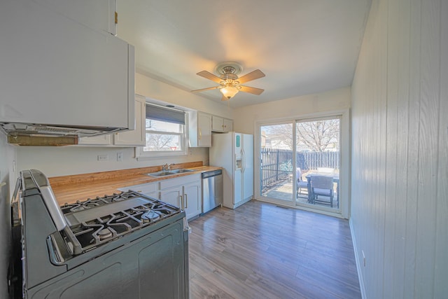 kitchen featuring stainless steel dishwasher, a ceiling fan, a sink, white fridge with ice dispenser, and gas stove