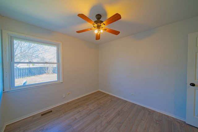 unfurnished room featuring baseboards, a ceiling fan, wood finished floors, and visible vents