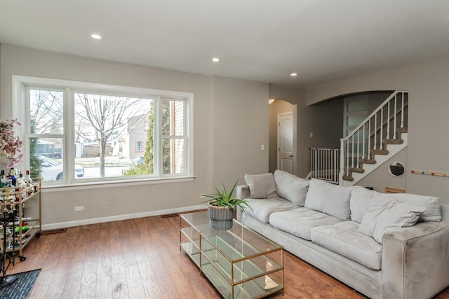 living room with arched walkways, a healthy amount of sunlight, baseboards, and hardwood / wood-style flooring
