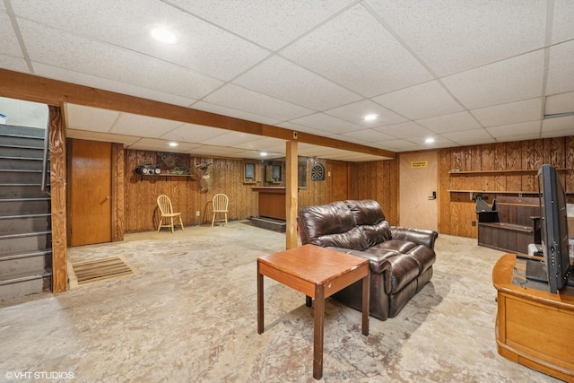 living room featuring stairway, wooden walls, a paneled ceiling, and recessed lighting