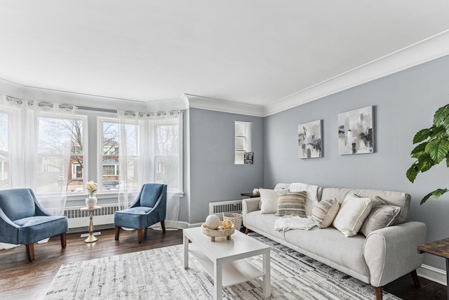 living room featuring visible vents, baseboards, crown molding, and wood finished floors