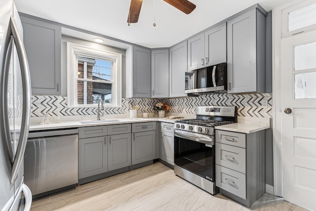 kitchen with gray cabinets, a sink, and stainless steel appliances