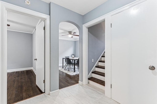 hallway featuring baseboards, ornamental molding, and stairs